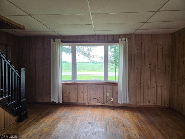 1264 389th Ave NE, Stanchfield Twp, MN 55080 - empty room with a paneled ceiling, wood-type flooring, stairway, wooden walls, and plenty of natural light