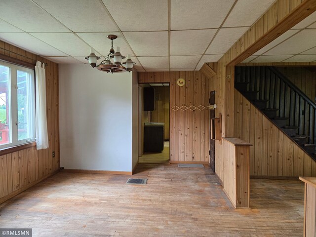 1264 389th Ave NE, Stanchfield Twp, MN 55080 - unfurnished dining area featuring wooden walls, light wood finished floors, a drop ceiling, stairs, and a chandelier