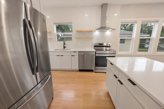 730 13th Ave S, Saint Cloud, MN 56301 - kitchen featuring appliances with stainless steel finishes, wall chimney range hood, decorative backsplash, light wood-type flooring, and white cabinets