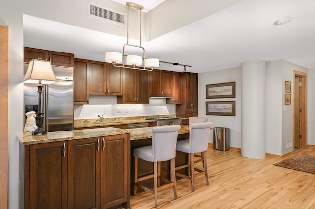 1120 2nd St Unit 1002, Minneapolis, MN 55415 - kitchen featuring light wood-style floors, a breakfast bar, light stone counters, decorative light fixtures, and rail lighting