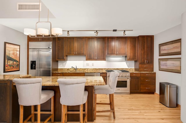 1120 2nd St Unit 1002, Minneapolis, MN 55415 - kitchen with high quality appliances, track lighting, light wood-style floors, a kitchen bar, and pendant lighting