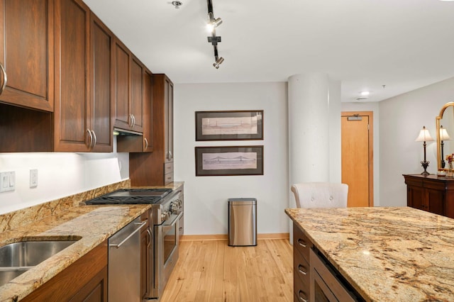 1120 2nd St Unit 1002, Minneapolis, MN 55415 - kitchen featuring appliances with stainless steel finishes, light wood-type flooring, light stone countertops, and track lighting