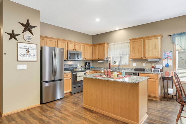 9775 Olive St NW, Coon Rapids, MN 55433 - kitchen featuring stainless steel appliances, dark wood finished floors, a center island, light brown cabinetry, and light stone counters