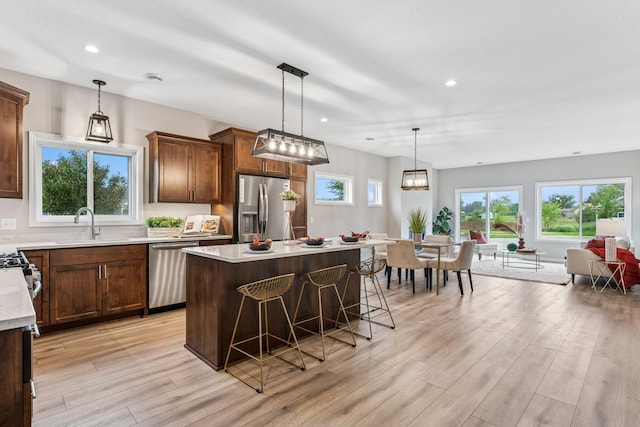 4838 Education Dr N, Hugo, MN 55038 - kitchen featuring appliances with stainless steel finishes, light wood-style flooring, a center island, light countertops, and a kitchen breakfast bar