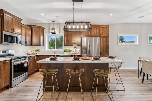 4838 Education Dr N, Hugo, MN 55038 - kitchen with stainless steel appliances, a breakfast bar area, a kitchen island, light wood finished floors, and recessed lighting
