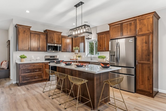 4838 Education Dr N, Hugo, MN 55038 - kitchen featuring stainless steel appliances, a kitchen breakfast bar, light wood-type flooring, a center island, and light countertops