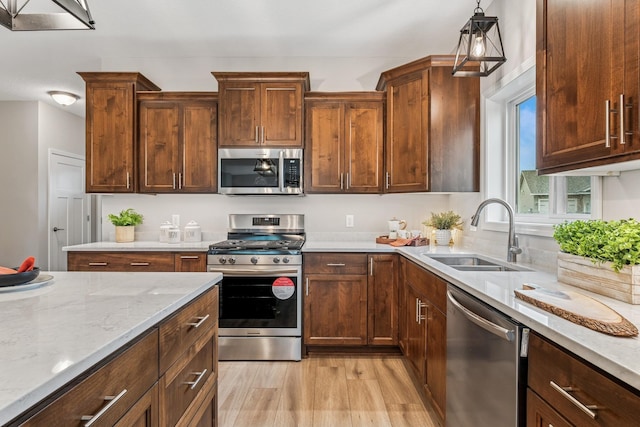 4838 Education Dr N, Hugo, MN 55038 - kitchen featuring stainless steel appliances, light wood-style flooring, light stone counters, and hanging light fixtures