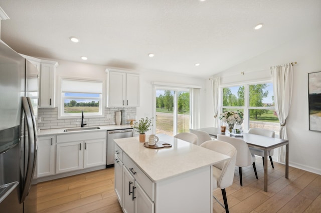 26645 8th St W, Zimmerman, MN 55398 - kitchen with appliances with stainless steel finishes, a kitchen bar, light wood finished floors, healthy amount of natural light, and vaulted ceiling