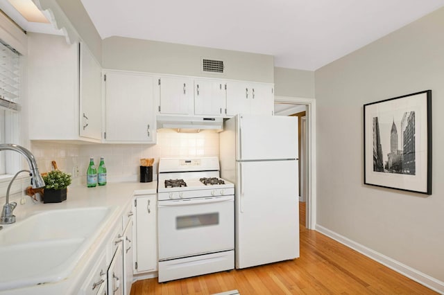 4604 39th St, Saint Louis Park, MN 55416 - kitchen with white appliances, under cabinet range hood, tasteful backsplash, light wood finished floors, and white cabinets