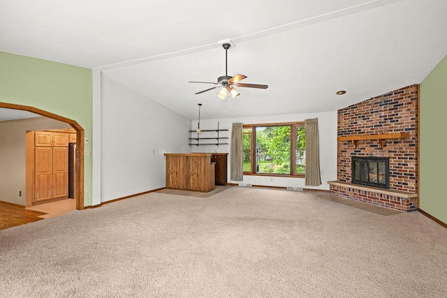 5120 Juniata St, Duluth, MN 55804 - unfurnished living room featuring carpet floors, ceiling fan, a fireplace, arched walkways, and bar area