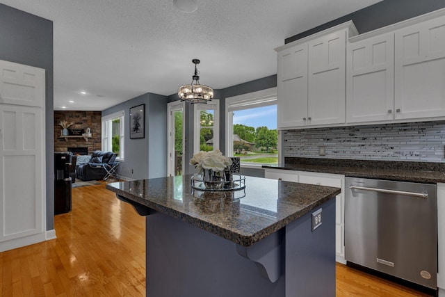 1302 Grizzly Ln, Sartell, MN 56377 - kitchen featuring stainless steel dishwasher, white cabinets, light wood-style flooring, backsplash, and a textured ceiling