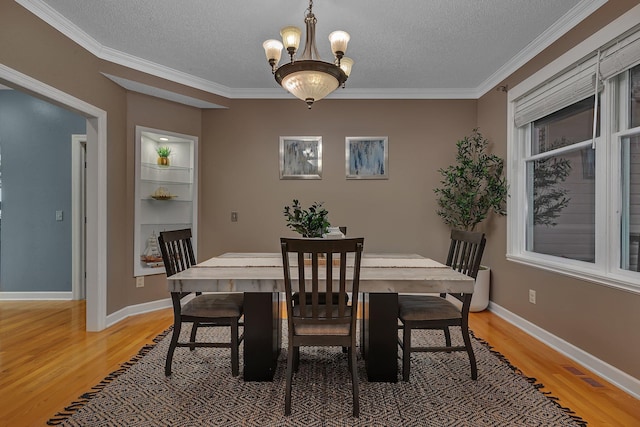 1302 Grizzly Ln, Sartell, MN 56377 - dining space with light wood-style flooring, a chandelier, a textured ceiling, and crown molding