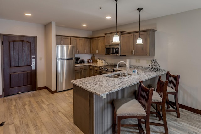 502 Cleveland Blvd Unit 3200, Walker, MN 56484 - kitchen with stainless steel appliances, a peninsula, light wood-style flooring, a breakfast bar, and light stone countertops