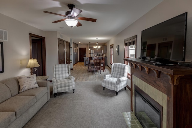 502 Cleveland Blvd Unit 3200, Walker, MN 56484 - living room featuring a chandelier, a tile fireplace, ceiling fan, light carpet, and light wood-style flooring