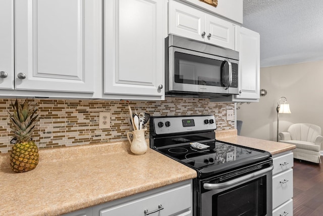 1150 Dellwood St S Unit 306, Cambridge, MN 55008 - kitchen featuring stainless steel appliances, white cabinetry, light countertops, dark wood finished floors, and decorative backsplash