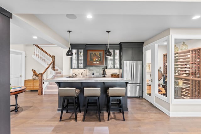 1595 Locust Hills Cir, Wayzata, MN 55391 - kitchen featuring freestanding refrigerator, light countertops, a kitchen breakfast bar, glass insert cabinets, and tasteful backsplash