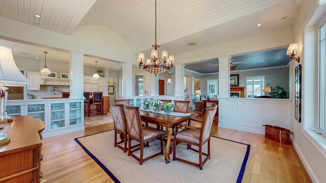 830 Prairie Island Rd N, Winona, MN 55987 - dining area featuring decorative columns, vaulted ceiling, light wood-style flooring, wooden ceiling, and wainscoting