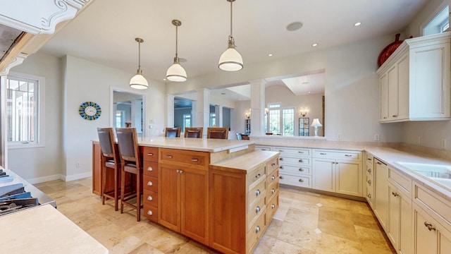 830 Prairie Island Rd N, Winona, MN 55987 - kitchen featuring ornate columns, light countertops, a kitchen island, pendant lighting, and a breakfast bar