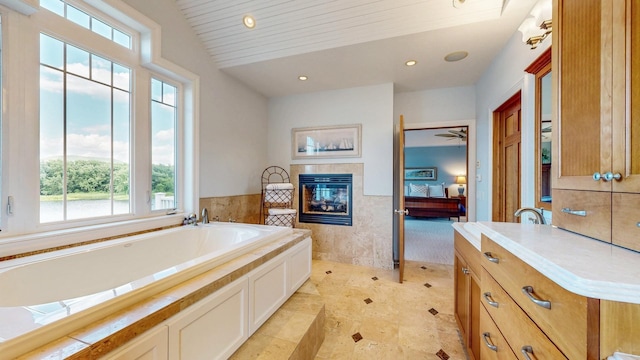 830 Prairie Island Rd N, Winona, MN 55987 - ensuite bathroom featuring a fireplace, a garden tub, recessed lighting, vanity, and a wainscoted wall