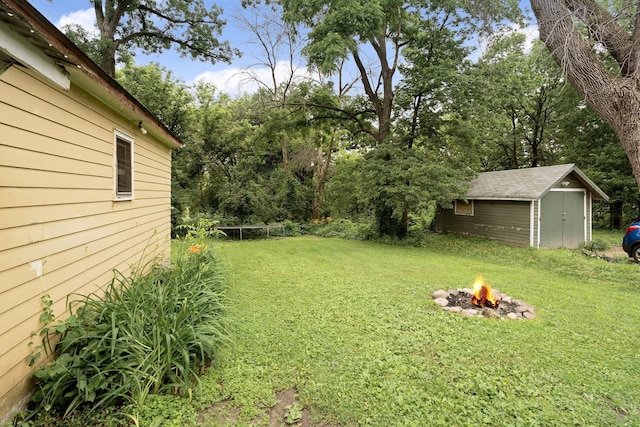 208 12th St SE, Austin, MN 55912 - view of green lawn with an outdoor fire pit, a storage shed, and view of wooded area