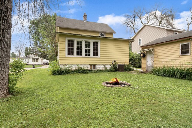 208 12th St SE, Austin, MN 55912 - rear view of property featuring a fire pit, a chimney, and a lawn