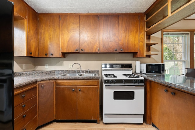208 12th St SE, Austin, MN 55912 - kitchen with white range with gas cooktop, open shelves, light wood finished floors, brown cabinets, and a textured ceiling
