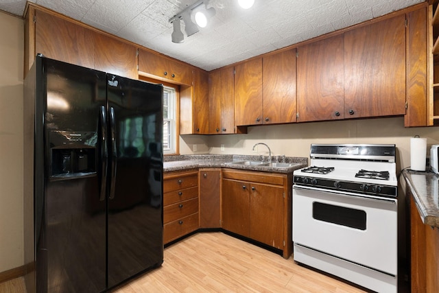 208 12th St SE, Austin, MN 55912 - kitchen with black fridge, white gas range oven, brown cabinets, and light wood-style floors