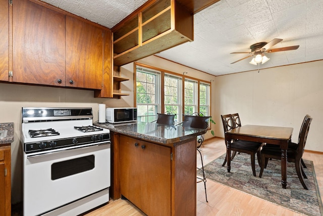 208 12th St SE, Austin, MN 55912 - kitchen featuring white range with gas stovetop, open shelves, a peninsula, brown cabinetry, and light wood finished floors