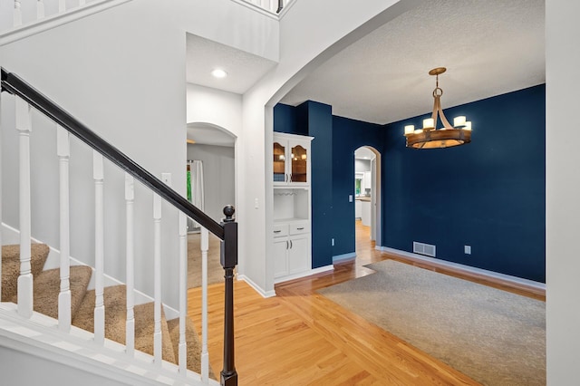 2403 Meadow Dr, Buffalo, MN 55313 - foyer with arched walkways, light wood-style flooring, a chandelier, and stairs