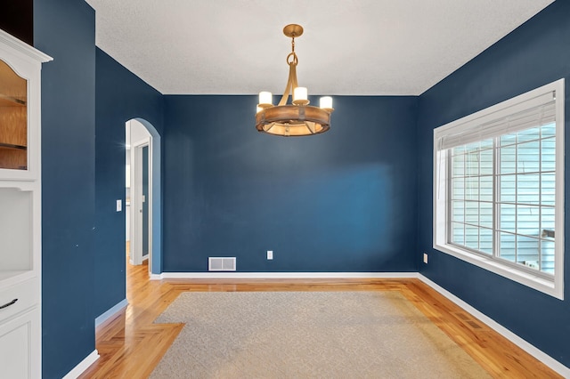 2403 Meadow Dr, Buffalo, MN 55313 - empty room with a chandelier, arched walkways, and light wood-type flooring