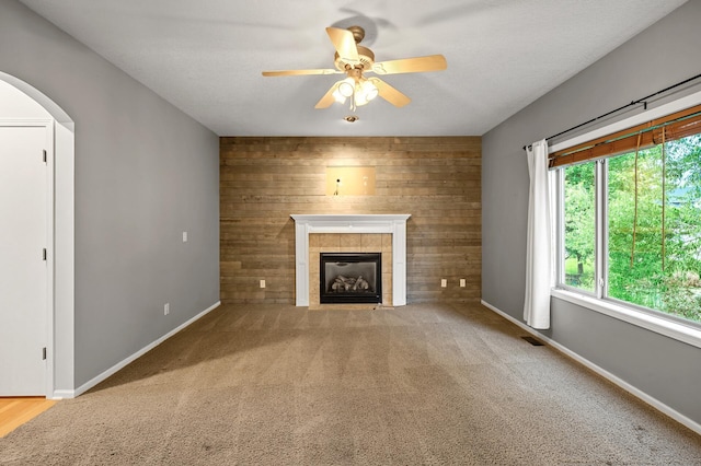 2403 Meadow Dr, Buffalo, MN 55313 - unfurnished living room featuring a tile fireplace, arched walkways, ceiling fan, carpet, and wooden walls