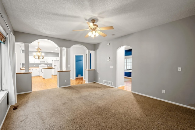 2403 Meadow Dr, Buffalo, MN 55313 - unfurnished living room featuring arched walkways, light colored carpet, ceiling fan, a chandelier, and a textured ceiling