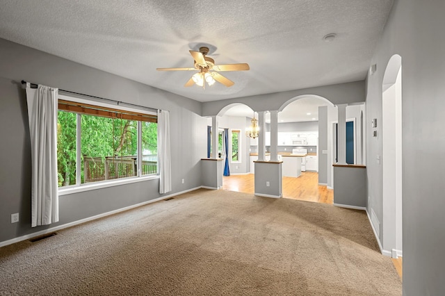2403 Meadow Dr, Buffalo, MN 55313 - unfurnished living room featuring light carpet, arched walkways, ceiling fan, ornate columns, and a textured ceiling
