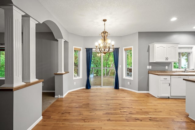 2403 Meadow Dr, Buffalo, MN 55313 - kitchen featuring white dishwasher, ornate columns, white cabinetry, light wood-type flooring, and a chandelier