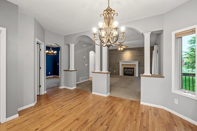 2403 Meadow Dr, Buffalo, MN 55313 - unfurnished living room with a chandelier, arched walkways, light wood-style flooring, a glass covered fireplace, and ornate columns