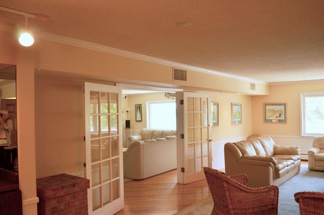 4387 Wilshire Blvd Unit 307, Mound, MN 55364 - living area featuring french doors, crown molding, a textured ceiling, light wood finished floors, and a wainscoted wall