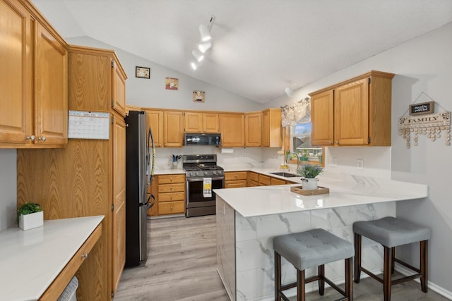 7175 Upper 157th St W, Apple Valley, MN 55124 - kitchen featuring stainless steel appliances, vaulted ceiling, a peninsula, light wood-type flooring, and a breakfast bar area