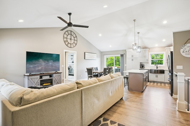 1623 Otter Way, New Richmond, WI 54017 - living area featuring healthy amount of natural light, light wood-style floors, a glass covered fireplace, a ceiling fan, and lofted ceiling