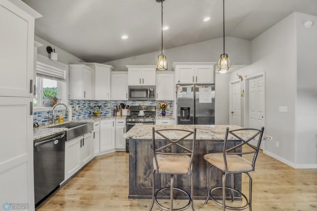 1334 6th St NW, Fargo, ND 58078 - kitchen featuring appliances with stainless steel finishes, decorative backsplash, white cabinets, a center island, and vaulted ceiling