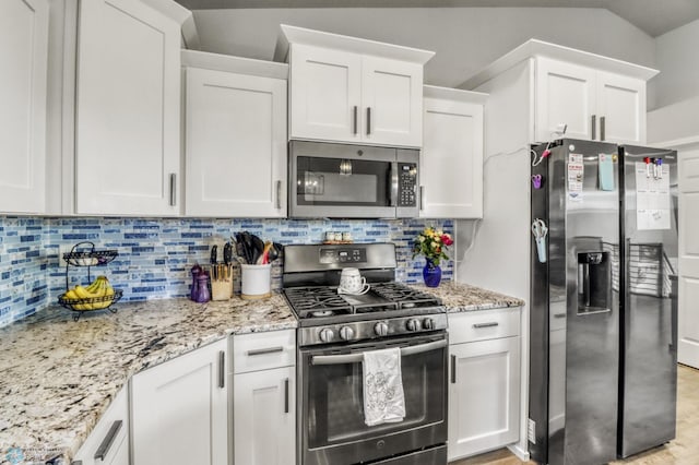 1334 6th St NW, Fargo, ND 58078 - kitchen featuring stainless steel appliances, white cabinets, light stone counters, and tasteful backsplash