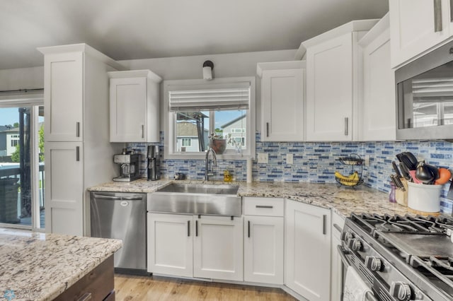 1334 6th St NW, Fargo, ND 58078 - kitchen with appliances with stainless steel finishes, white cabinetry, tasteful backsplash, and light stone countertops