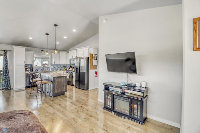1334 6th St NW, Fargo, ND 58078 - kitchen featuring appliances with stainless steel finishes, white cabinets, decorative backsplash, lofted ceiling, and a center island