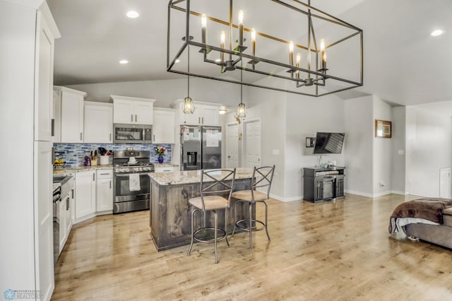 1334 6th St NW, Fargo, ND 58078 - kitchen featuring appliances with stainless steel finishes, open floor plan, a center island, vaulted ceiling, and tasteful backsplash