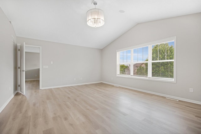 6758 Troy Ln N, Maple Grove, MN 55311 - unfurnished room featuring lofted ceiling, a chandelier, and light wood-style floors