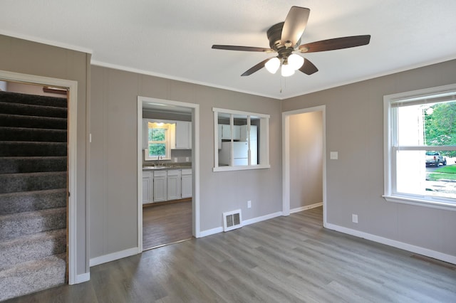 913 12th Ave SE, Austin, MN 55912 - empty room with a ceiling fan, wood finished floors, crown molding, and stairway