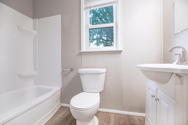 913 12th Ave SE, Austin, MN 55912 - bathroom with wood finished floors, vanity, bathtub / shower combination, and tile walls