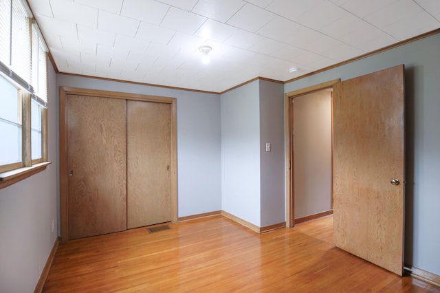 913 12th Ave SE, Austin, MN 55912 - unfurnished bedroom featuring crown molding, light wood-style floors, and a closet