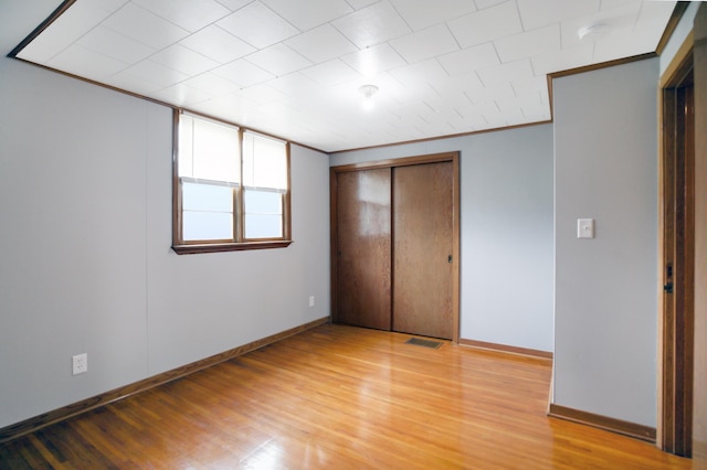 913 12th Ave SE, Austin, MN 55912 - unfurnished bedroom featuring light wood-type flooring, crown molding, and a closet