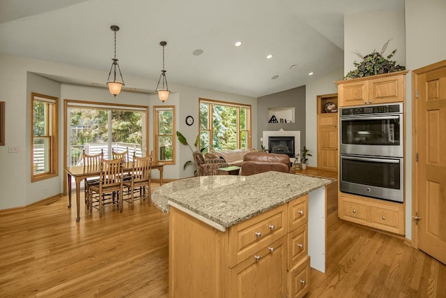 485 Preserve Path W, Saint Paul, MN 55118 - kitchen featuring double oven, light wood finished floors, a center island, a glass covered fireplace, and light stone countertops