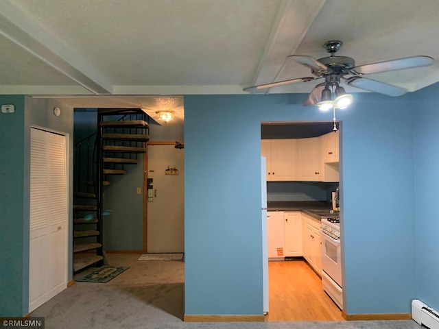 7236 72nd Ln N Unit 202, Brooklyn Park, MN 55428 - kitchen with white gas range, baseboard heating, a ceiling fan, dark countertops, and white cabinetry